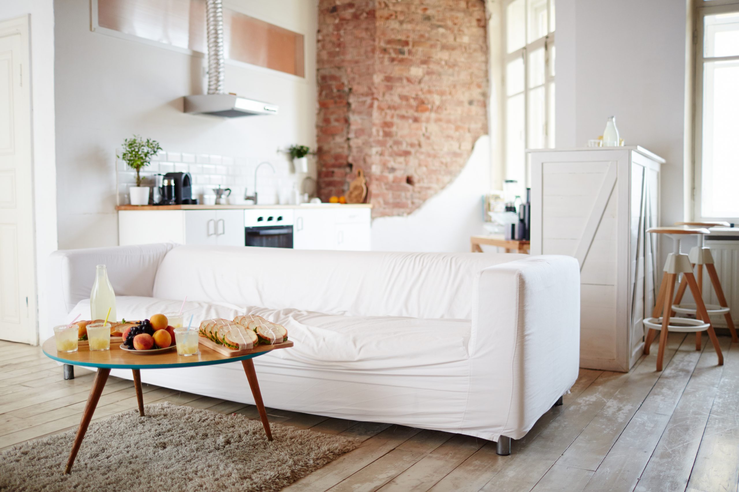 Empty room with white sofa by wooden table with festive snack prepared for gathering of friends